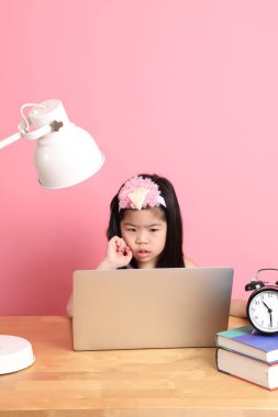 The cute Asian girl learning from internet by laptop with the pink background.