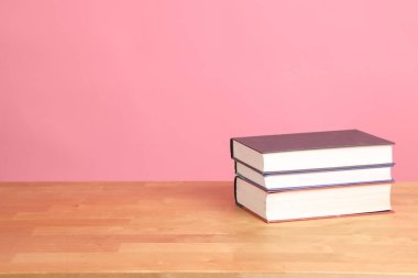 Çalışma masasındaki pembe arkaplanlı kitapların resmi..