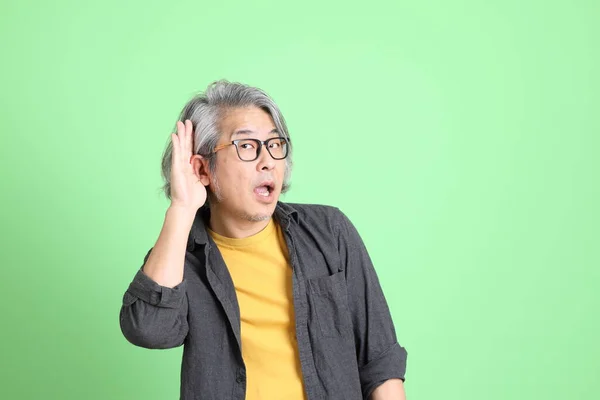薄緑色の背景に立ってスマートなカジュアルを身に着けているアジアの老人 — ストック写真