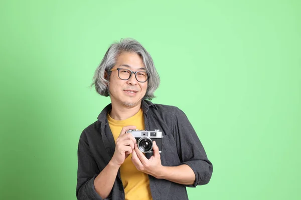 薄緑色の背景に立ってスマートなカジュアルを身に着けているアジアの老人 — ストック写真