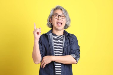 Sarı arka planda kot giymiş kıdemli Asyalı adam..