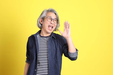 Sarı arka planda kot giymiş kıdemli Asyalı adam..