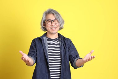 Sarı arka planda kot giymiş kıdemli Asyalı adam..