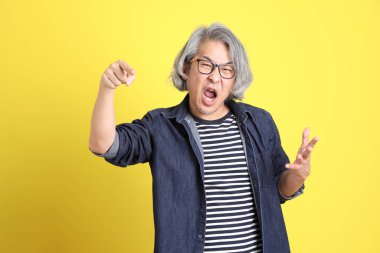 Sarı arka planda kot giymiş kıdemli Asyalı adam..