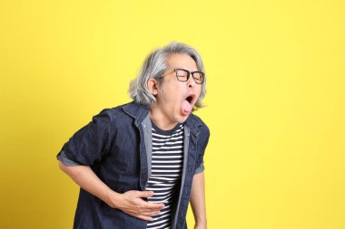 Sarı arka planda kot giymiş kıdemli Asyalı adam..