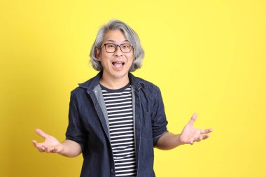 Sarı arka planda kot giymiş kıdemli Asyalı adam..