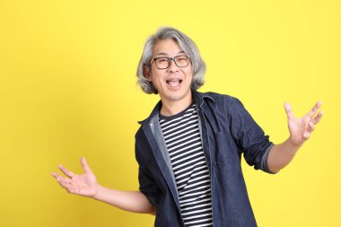 Sarı arka planda kot giymiş kıdemli Asyalı adam..