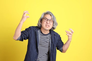 Sarı arka planda kot giymiş kıdemli Asyalı adam..