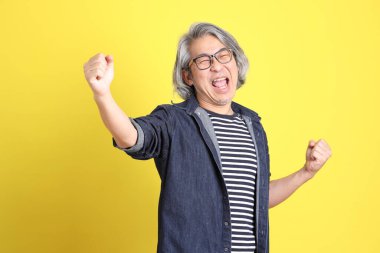 Sarı arka planda kot giymiş kıdemli Asyalı adam..