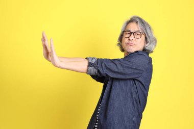 Sarı arka planda kot giymiş kıdemli Asyalı adam..