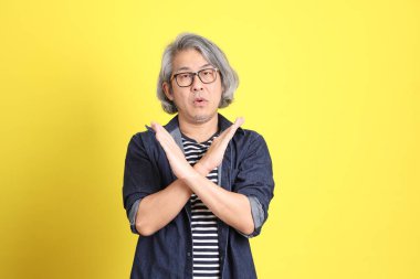 Sarı arka planda kot giymiş kıdemli Asyalı adam..