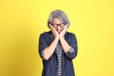 Sarı arka planda kot giymiş kıdemli Asyalı adam..