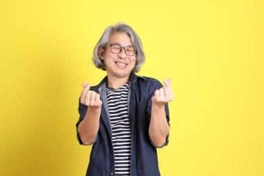 Sarı arka planda kot giymiş kıdemli Asyalı adam..