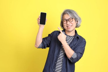 Sarı arka planda kot giymiş kıdemli Asyalı adam..