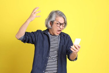 Sarı arka planda kot giymiş kıdemli Asyalı adam..