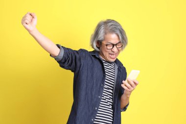 Sarı arka planda kot giymiş kıdemli Asyalı adam..