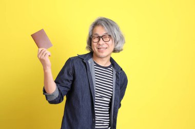 Sarı arka planda kot giymiş kıdemli Asyalı adam..