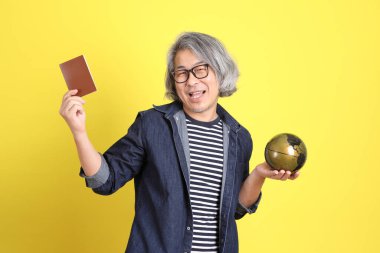 Sarı arka planda kot giymiş kıdemli Asyalı adam..