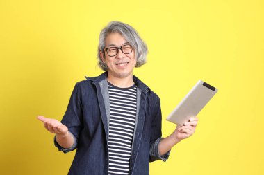 Sarı arka planda kot giymiş kıdemli Asyalı adam..