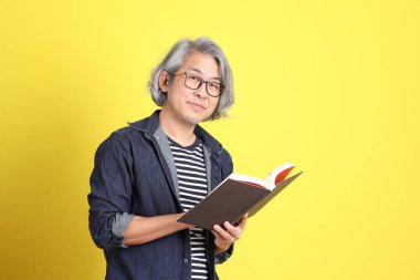 Sarı arka planda kot giymiş kıdemli Asyalı adam..