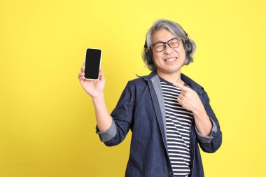 Sarı arka planda kot giymiş kıdemli Asyalı adam..