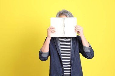 Sarı arka planda kot giymiş kıdemli Asyalı adam..