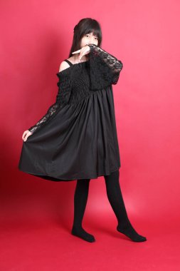 Kırmızı arka planda duran şirin gotik elbiseli Asyalı genç kız..