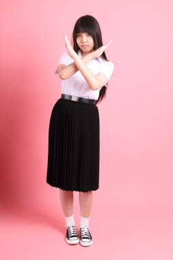 Üniversite üniformalı genç Asyalı kız pembe arka planda duruyor..