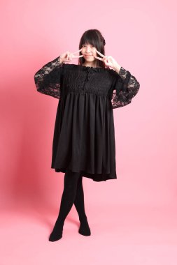 Pembe arka planda gotik giyinmiş yakışıklı Asyalı kız.