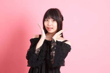 Pembe arka planda gotik giyinmiş yakışıklı Asyalı kız.