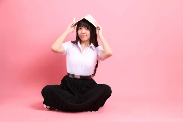 穿着校服坐在粉色背景上的亚洲少女 — 图库照片
