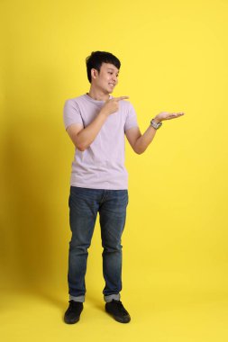 Sarı arka planda duran Asyalı genç adam..