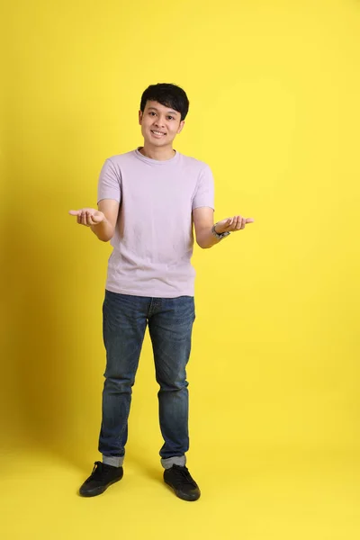 Νεαρός Ενήλικας Ασιάτης Που Στέκεται Στο Κίτρινο Φόντο — Φωτογραφία Αρχείου