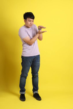 Sarı arka planda duran Asyalı genç adam..