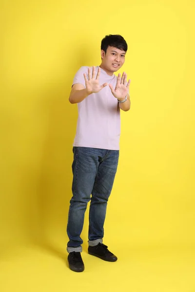 站在黄色背景上的年轻的亚洲男子 — 图库照片