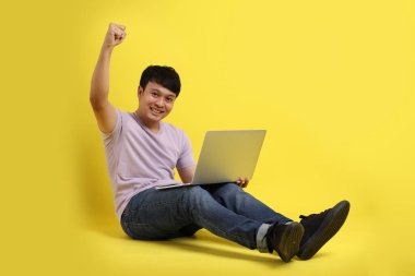 Sarı arka planda oturan genç Asyalı adam..