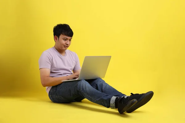 年轻的亚洲男子坐在黄色的背景上 — 图库照片