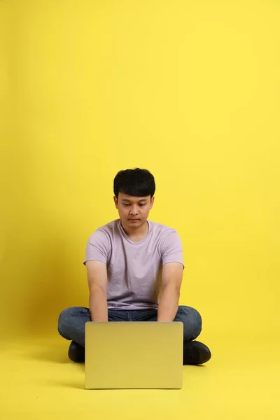 Νεαρός Ενήλικας Ασιάτης Που Κάθεται Στο Κίτρινο Φόντο — Φωτογραφία Αρχείου
