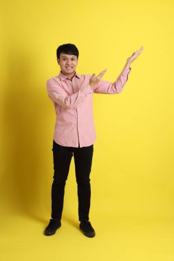 Sarı arka planda duran pembe gömlekli Asyalı adam..