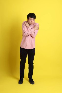 Sarı arka planda duran pembe gömlekli Asyalı adam..