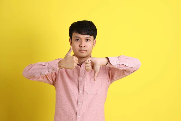 Sarı Arka Planda Duran Pembe Gömlekli Asyalı Adam — Stok fotoğraf
