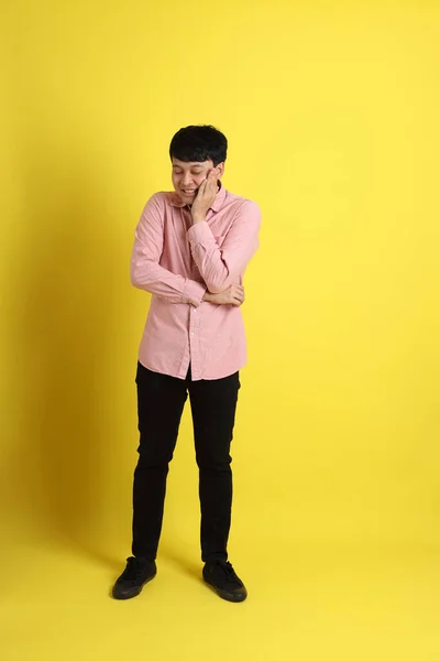 黄色の背景にピンクのシャツを着たアジア人 — ストック写真