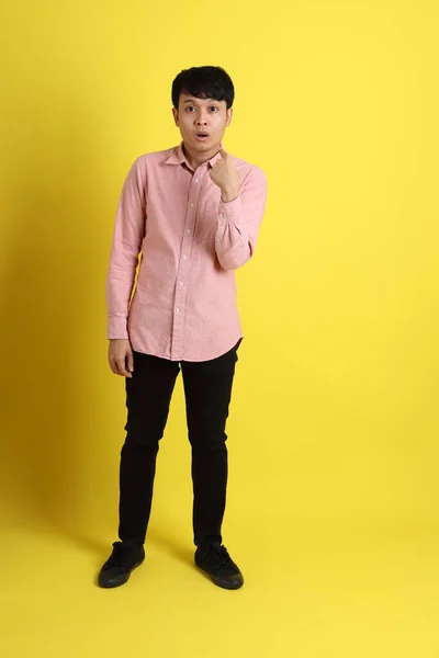 黄色の背景にピンクのシャツを着たアジア人 — ストック写真