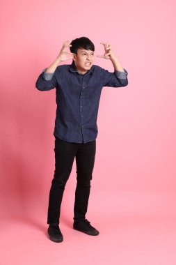 Pembe arka planda duran genç Asyalı adam..