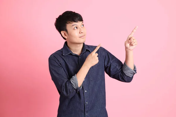 ピンクの背景に立つ若い大人のアジア人男性 — ストック写真