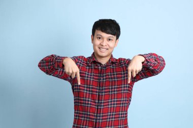 Mavi arka planda duran genç Asyalı adam..