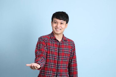 Mavi arka planda duran genç Asyalı adam..