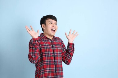 Mavi arka planda duran genç Asyalı adam..