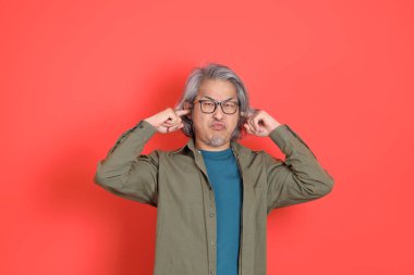 Turuncu arka planda günlük giysileri olan kıdemli Asyalı adam..