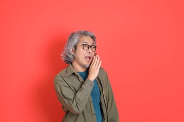 Turuncu arka planda günlük giysileri olan kıdemli Asyalı adam..